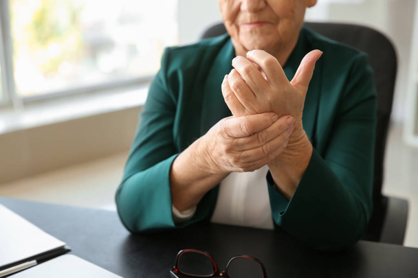 Senior woman suffering from pain in wrist indoors - Valokuva, kuva