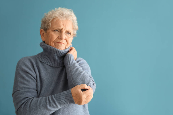 Senior woman suffering from pain in elbow on color background - Foto, Imagem