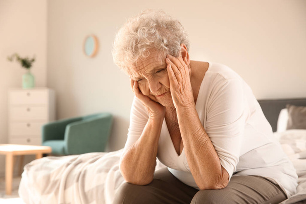 Senior woman suffering from headache at home - Foto, afbeelding