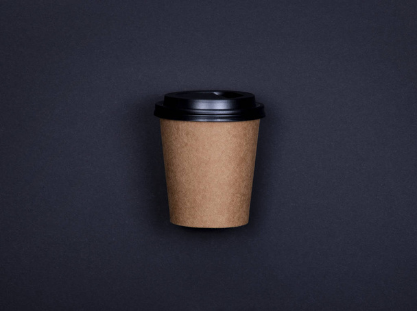 One brown craft paper cup of coffee to go on black background with copy space
. - Фото, изображение