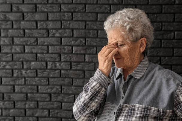 Seniorin leidet unter Kopfschmerzen auf dunklem Hintergrund - Foto, Bild