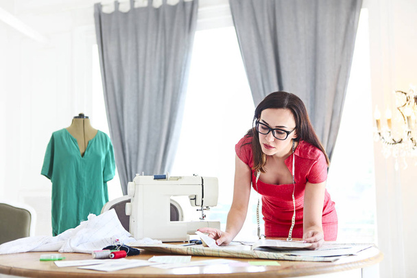 Дизайнер моди жінка працює над своїми дизайнами в студії
  - Фото, зображення