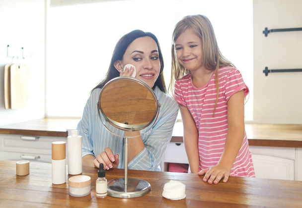 Bonito sorridente mãe e filha aplicando creme facial juntos
  - Foto, Imagem