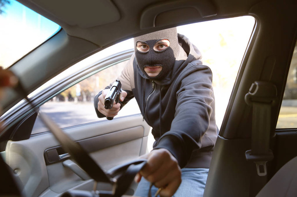 Вор с пистолетом крадет сумку из открытой машины
 - Фото, изображение