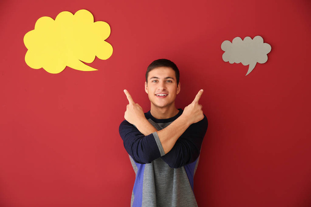 Young man with speech bubbles on color background - Photo, Image