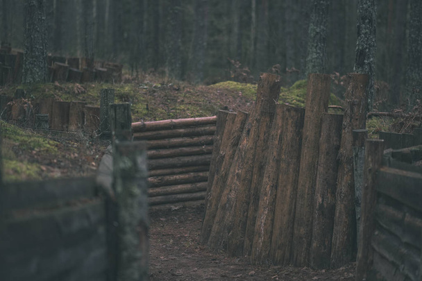old wooden trenshes in Latvia with barbed wire and guard posts. reconstruction of first world war. Lozmetejkalns. dark forest evening - vintage retro look - Photo, Image
