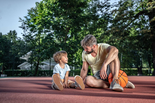 Padre e hijo en la cancha de baloncesto cerca de la casa
 - Foto, Imagen