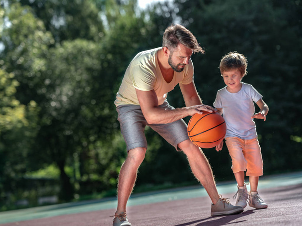 Отец и сын играют в баскетбол на открытом воздухе - Фото, изображение