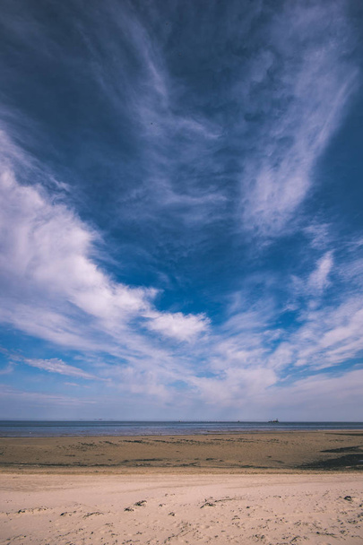 пустой морской пляж весной с некоторыми птицами и грузовыми кораблями на горизонте. голубое небо, без облаков - винтажный ретро взгляд
 - Фото, изображение