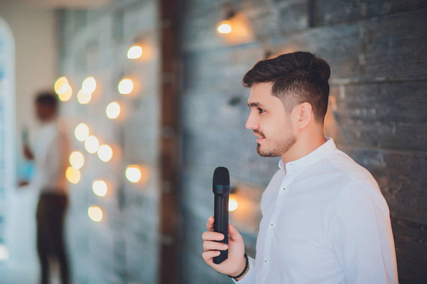 Showman interviewer with emotions. Young elegant man holding microphone against white background.Showman concept. - Foto, Bild