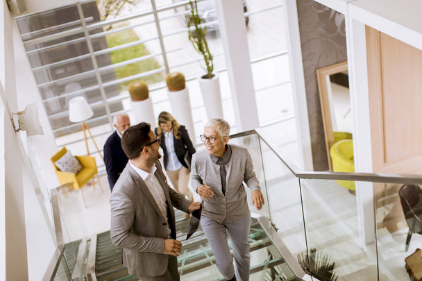 Group of businessmen and businesswomen walking and taking stairs in an office building - Photo, Image