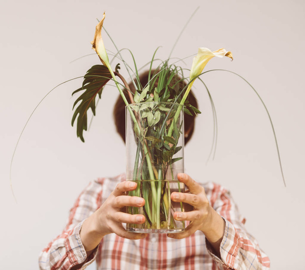 Mujer sosteniendo frente a su cara florero de flores con plantas muertas
 - Foto, imagen