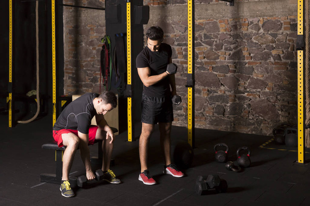 fitte Männer, die mit Trainern im Fitnessstudio trainieren. Dark-Photography-Konzept mit Kopierraum. - Foto, Bild