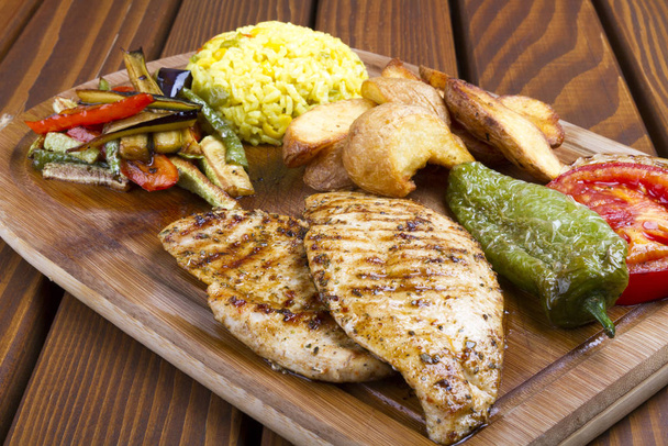 Grillezett csirkemell, friss zöldségek és burgonya beillesztés a háttérben fa asztal.  - Fotó, kép
