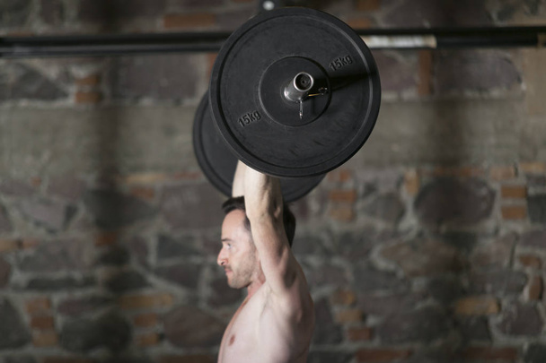 Topless sportowca praktykujących wyciągów olympic siłowni z cegły ściany tło. - Zdjęcie, obraz