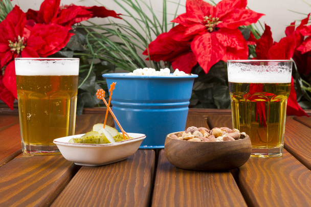 Dos vasos de cerveza de barril que sirven con nueces, palomitas de maíz y encurtidos en rodajas sobre fondo de mesa de madera
. - Foto, imagen