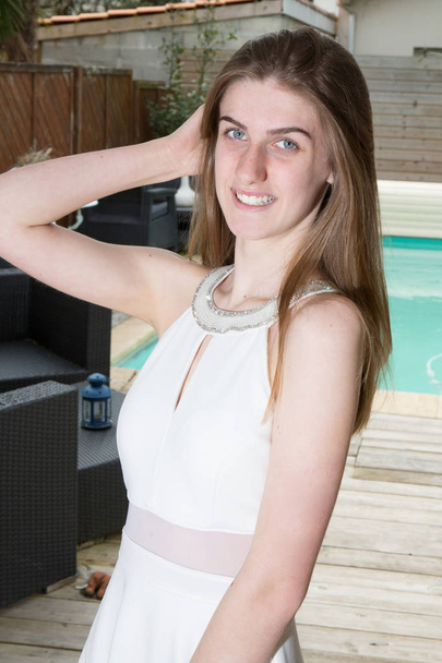Retrato de una chica feliz con ojos azules cerca de la piscina en el patio trasero de la casa de vacaciones
 - Foto, imagen