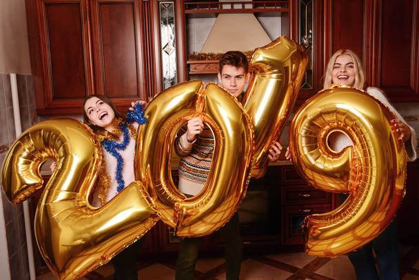 New 2019 Year is coming. Group of cheerful young people carrying gold colored numbers and have fun at the party. - Photo, Image