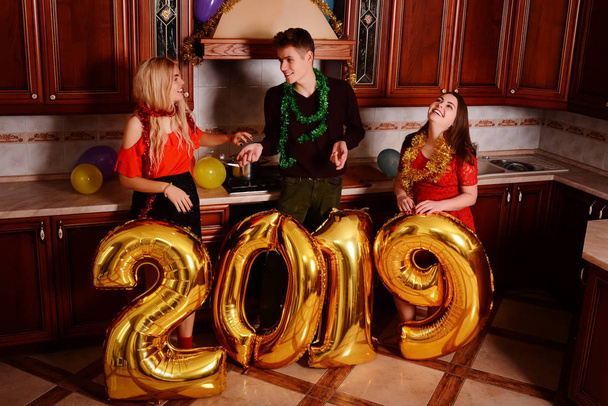 新しい 2019 年が来ています。金を運ぶ陽気な若者のグループ番号を色し、パーティで楽しい時を過す. - 写真・画像