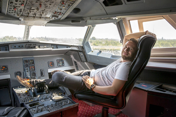 Jeune beau barbu blond dans le cockpit du pilote d'avion avec panneaux de contrôle. Le poste de pilotage est la zone, habituellement près de l'avant d'un aéronef ou d'un engin spatial, à partir de laquelle un pilote contrôle l'aéronef.
. - Photo, image
