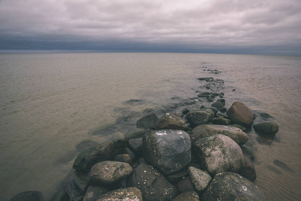 felsige Küste in Lettland mit fließendem Wasser im Meer und großen Felsen im Spätherbst. matte Farben - Vintage-Retro-Look - Foto, Bild