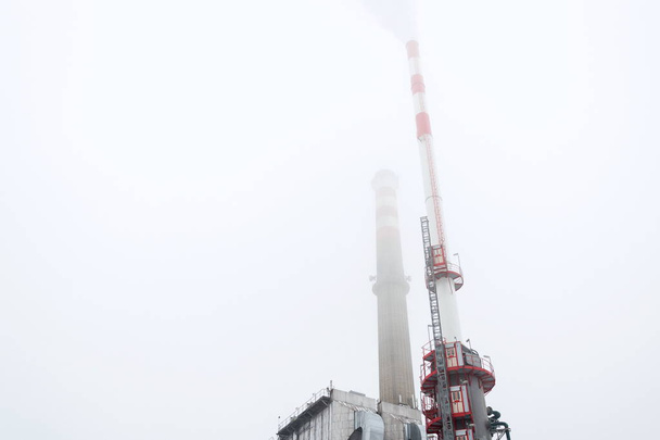 Vieja una nueva chimenea en la planta de calefacción cubierta de niebla, día nublado de invierno, vista de bajo ángulo, producción de energía, cambio climático y global, concepto de calentamiento
 - Foto, Imagen