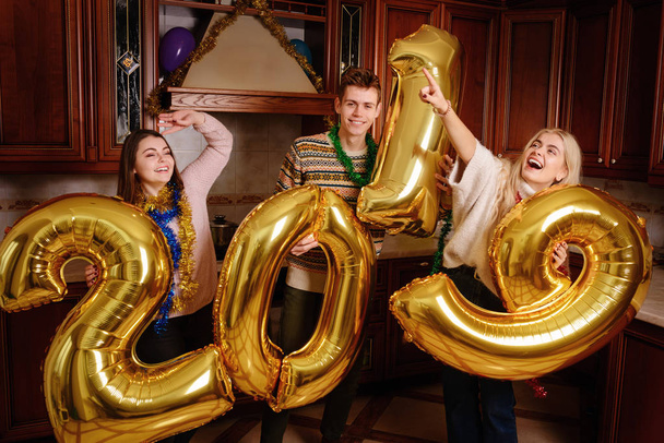 New 2019 Year is coming. Group of cheerful young people carrying gold colored numbers and have fun at the party. - Foto, imagen
