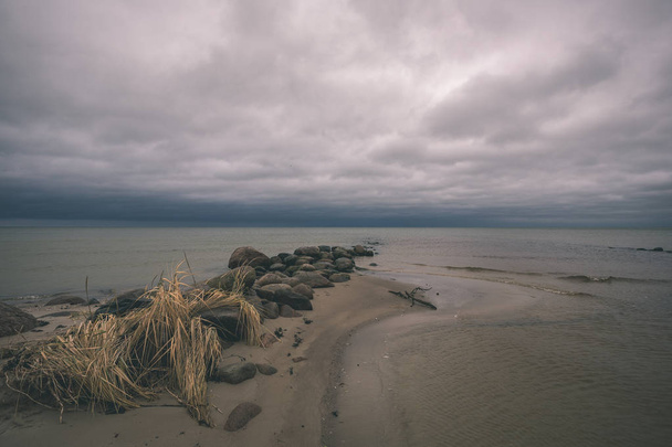 βραχώδη ακτή στη Λετονία με την ροή του νερού μέσα στη θάλασσα και μεγάλους βράχους στα τέλη του φθινοπώρου. φαίνονται θαμπά χρώματα - ρετρό παλιάς χρονολογίας - Φωτογραφία, εικόνα