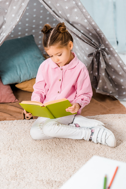 adorable child sitting on carpet and reading book - Photo, Image