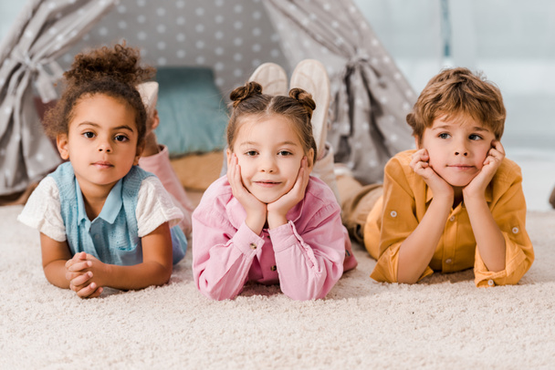 beaux enfants multiethniques allongés sur le tapis et regardant la caméra
  - Photo, image