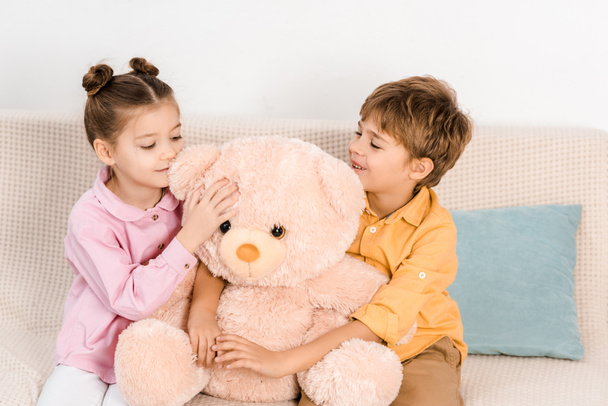 beautiful happy children sitting with pink teddy bear on couch - 写真・画像