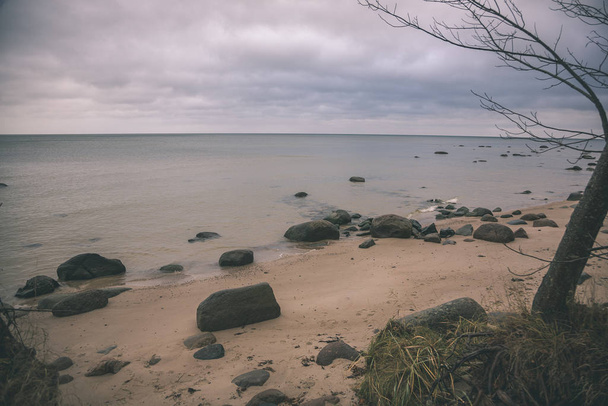 sziklás partvidék Lettországban áramlási víz a tengerben, és késő ősszel nagy sziklák. tompa - vintage retro színei - Fotó, kép