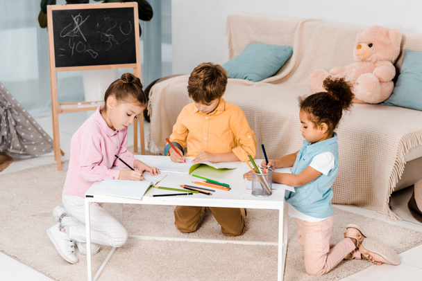 high angle view of adorable multiethnic children drawing and studying together  - Photo, Image