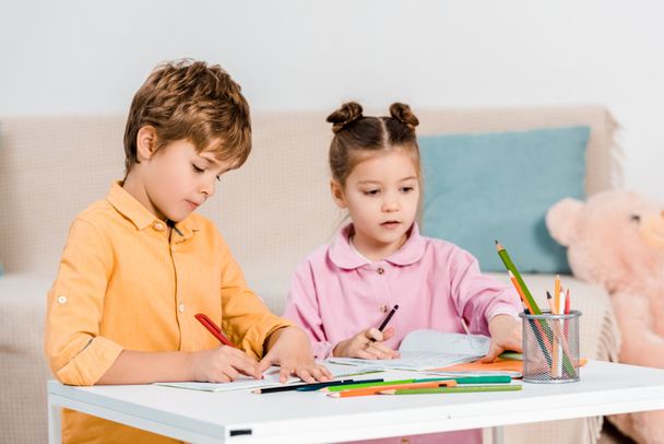 adorables niños pequeños escribiendo y estudiando juntos
  - Foto, Imagen
