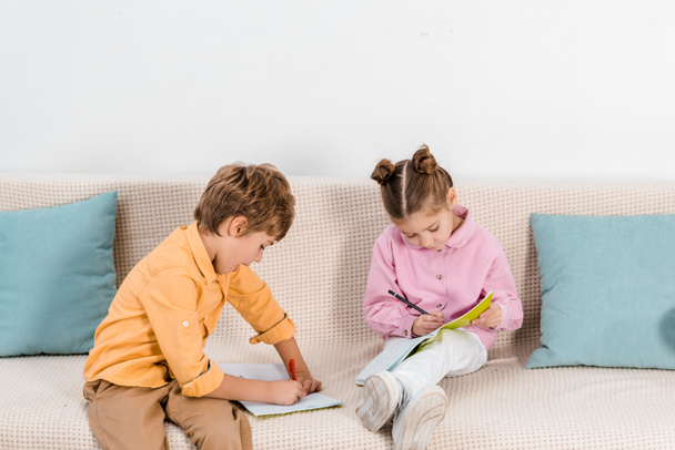 cute little kids sitting on sofa and drawing together - Φωτογραφία, εικόνα