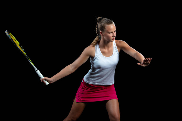 Portrait of beautiful woman playing tennis indoor. Isolated on black. - Photo, Image