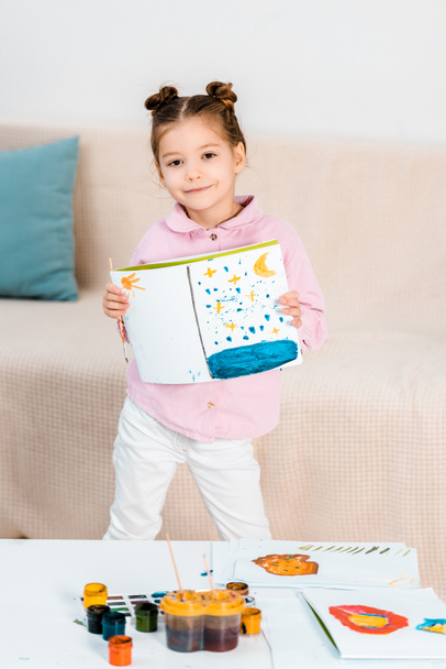 cute happy child holding picture and smiling at camera - Foto, Bild