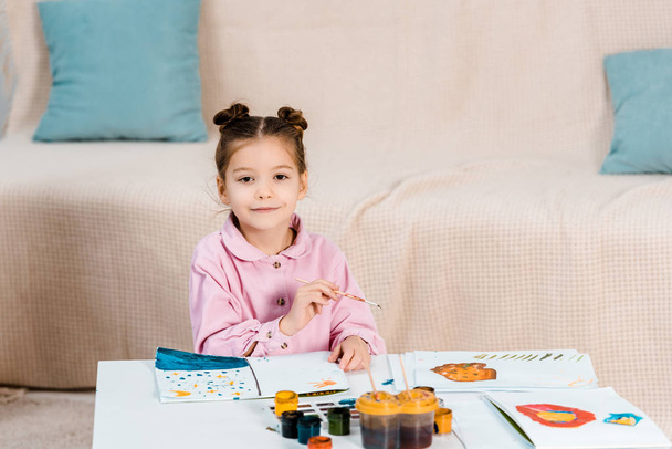 cute happy child painting pictures and smiling at camera - Fotoğraf, Görsel
