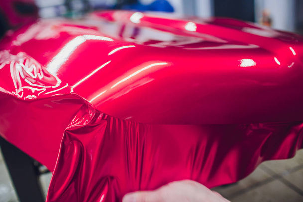 Car wrapping specialist putting vinyl foil or film on car wrapping protective film yacht, boat, ship, car, mobile home. pink red film hand pulls - 写真・画像