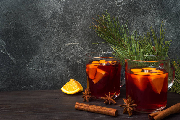 Christmas mulled red wine with spices and fruits on a wooden rustic table. Traditional hot drink at Christmas time. - Foto, afbeelding