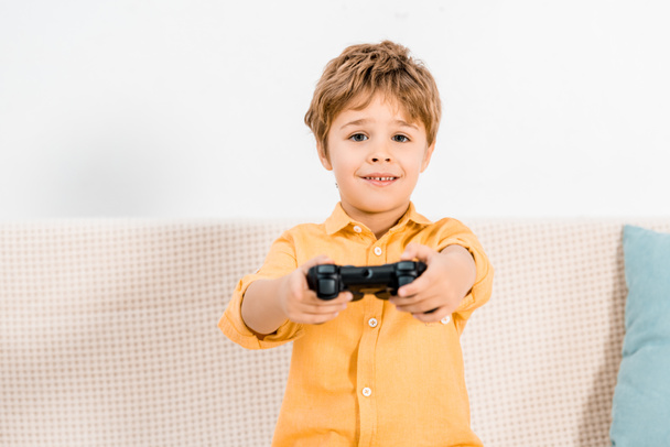 Sevimli küçük çocuk oyun çubuğu ve kameraya bakarak video oyun oynuyor - Fotoğraf, Görsel