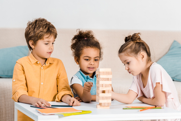 cute little multiracial children playing with wooden blocks on table - 写真・画像