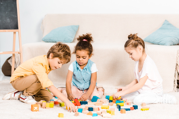 crianças pequenas bonitos brincando com cubos coloridos no tapete
   - Foto, Imagem