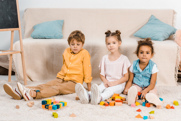 lindo multiétnicos niños jugando con cubos de colores y mirando a la cámara
  - Foto, Imagen