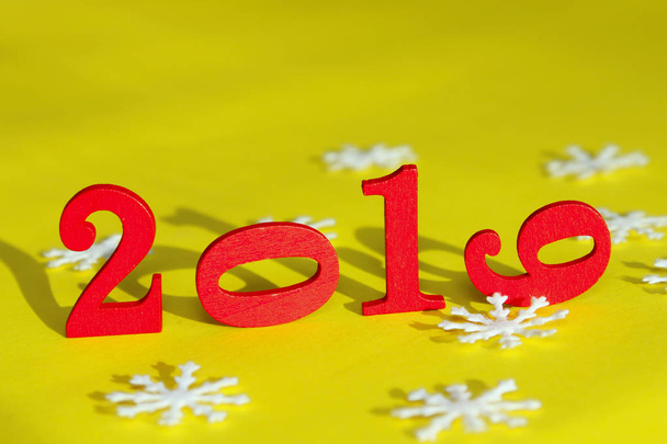 Christmas, Holidays, New Year Concept. Red Figures 2019 And White Snowflakes  Over Yellow Background. Colorful Background For New Year Card. - Photo, Image