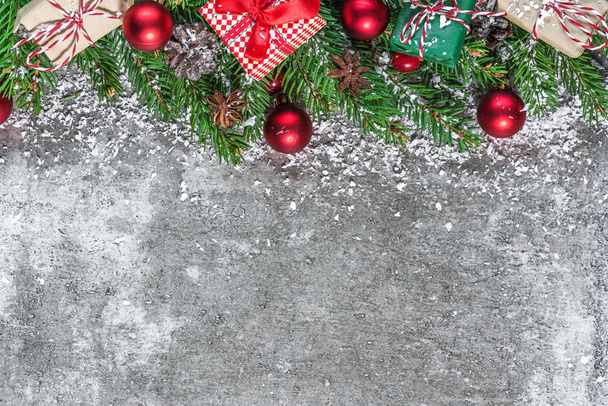karácsonyi dekoráció készült fenyő ágak, dekoráció, ajándék dobozok és fenyőtobozok a sötét kő asztal hóval borított. Karácsonyi háttér. Lapos feküdt. szemközti nézet másol hely - Fotó, kép