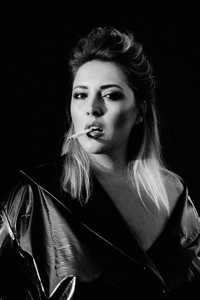 gorgeous young blond woman in leather coat smoking - Foto, imagen