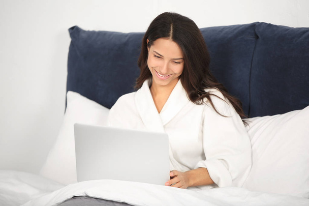Mujer joven con portátil descansando en la cama
 - Foto, Imagen