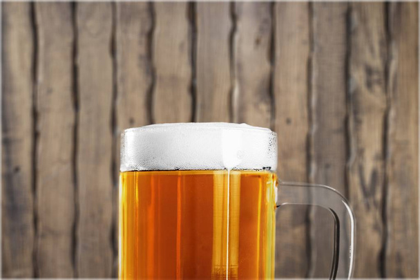 Mug of cold beer on wooden table - Фото, изображение