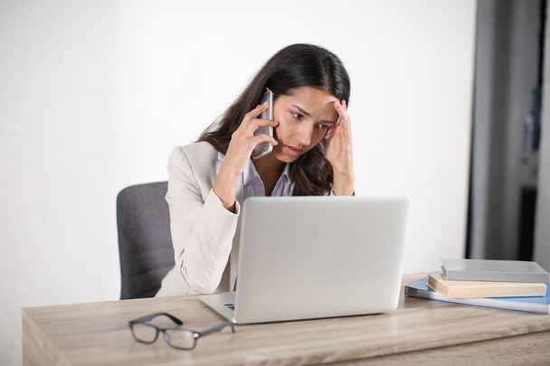 junge Frau mit Laptop telefoniert im Büro - Foto, Bild